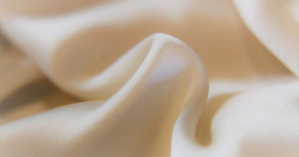 Close-up of smooth silk fabric with soft folds showing texture and drape