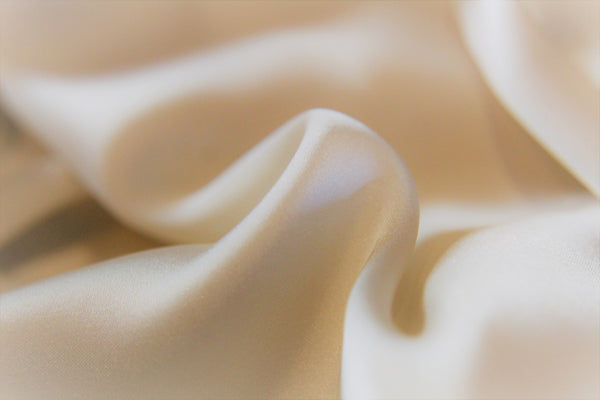 Close-up of smooth silk fabric with soft folds showing texture and drape