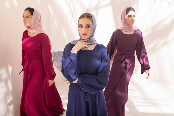 Three stylish women in elegant hijabs showcasing different colors in natural light