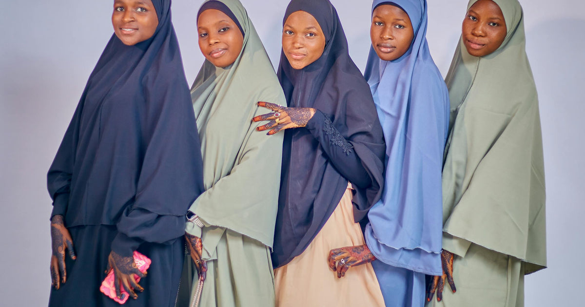 Five women wearing traditional hijabs in different colors posing together in a studio