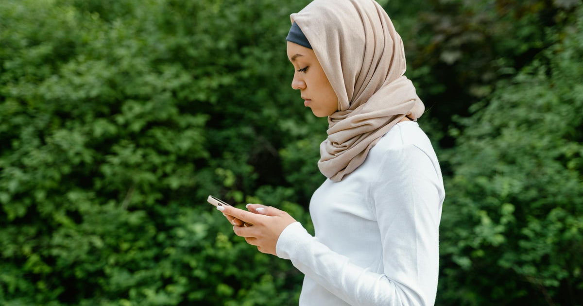 Muslim woman in hijab using a smartphone in a natural outdoor setting