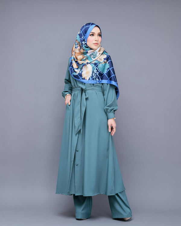Woman wearing floral printed chiffon hijab in teal outfit, studio shot